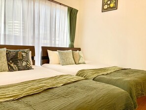 A hotel room with two beds, each with a green bedspread and matching pillows. - Neo Universal 04 (Osaka, Konohana, Nishikujo)