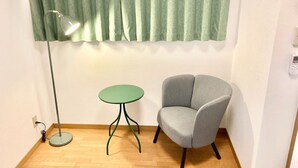 A room with a green curtain, a round table, a grey armchair, a floor lamp, and a wall socket. - Neo Universal 04 (Osaka, Konohana, Nishikujo)