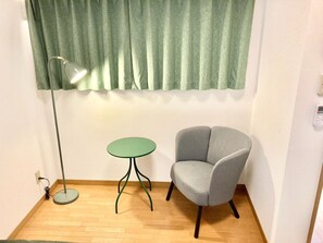 A room with a green curtain, a round table, a grey armchair, a floor lamp, and a wall socket. - Neo Universal 04 (Osaka, Konohana, Nishikujo)