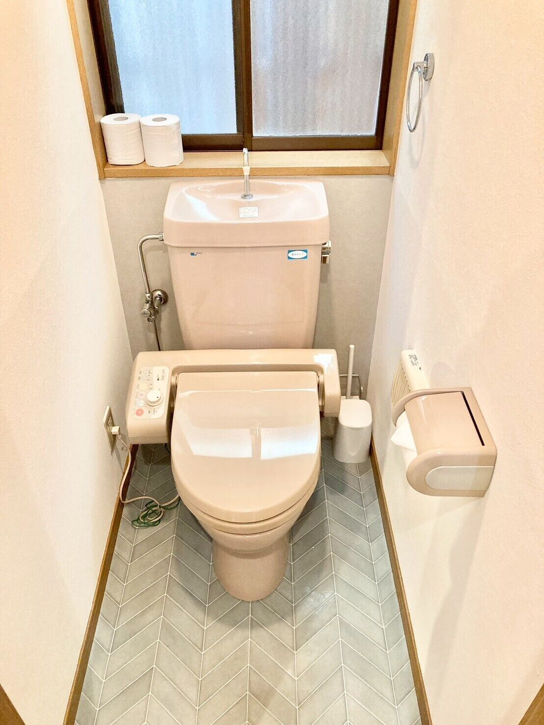 Ein kleines Badezimmer mit Toilette, Waschbecken und einem Fenster über dem Waschbecken.
