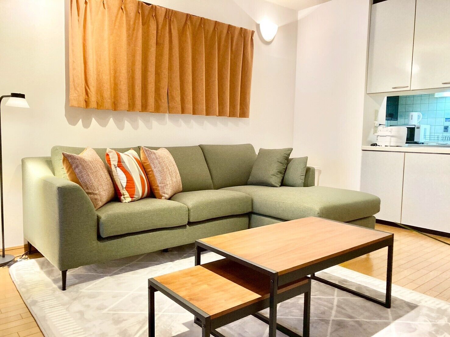 Ein modernes Wohnzimmer mit einem grünen Sofa, einem Holztisch und einem gemusterten Teppich.