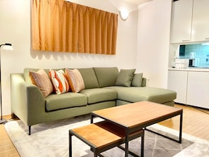 A modern living room with a green sofa, a wooden coffee table, and a patterned rug. - Neo Universal 04 (Osaka, Konohana, Nishikujo)