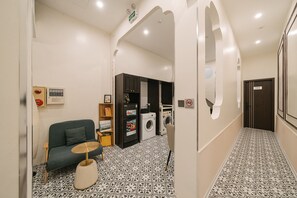 A hallway with a sofa, a small table, a washing machine, and a cabinet. - Anora de Van - Cozy hotel in tranquil Hà Nội with big balcony and bathtub (Hà Nội)