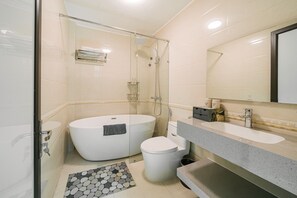 Ein modernes Badezimmer mit einer Glaskabine zur Dusche, einer freistehenden Badewanne, einer Toilette und einem Waschtisch mit Spiegel.