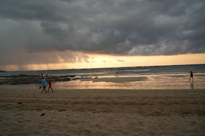A beach with people walking, boats in the water, and a cloudy sky. - Poolside room with private balcony in Tamarindo, self check-in (Tamarindo)