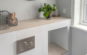 Eine Küchenarbeitsplatte mit weißer Oberfläche, einem Metallkorb und einem Blumentopf.