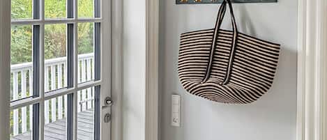 Une porte donnant sur une terrasse en bois, un porte-manteau mural avec des crochets et une prise de courant.