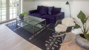 A modern living room with a glass coffee table, a purple sofa, and a rocking chair. - 4 bedroom gorgeous home in Karrebæksminde (Karrebæksminde)