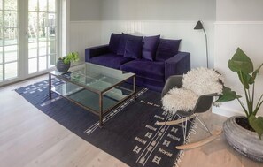 Ein modernes Wohnzimmer mit einem Glastisch, einem violetten Sofa und einem Schaukelstuhl.