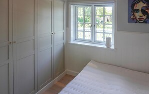 Ein Schlafzimmer mit Bett, Fenster und Kleiderschrank.