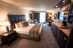 Een hotelkamer met een groot bed, een bureau, een televisie en een minibar.