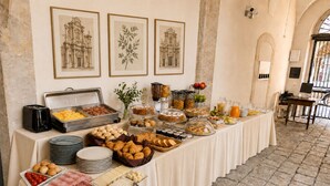A buffet table with various food items and a coffee station, set in a room with stone walls and framed pictures on the wall.