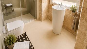 Une salle de bain moderne avec une douche en verre, un lavabo blanc et une fenêtre donnant sur un beau paysage.