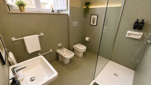 A modern bathroom with a sink, bidet, toilet, and shower.
