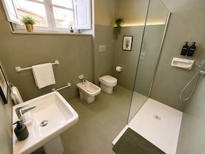 A modern bathroom with a sink, bidet, toilet, and shower.