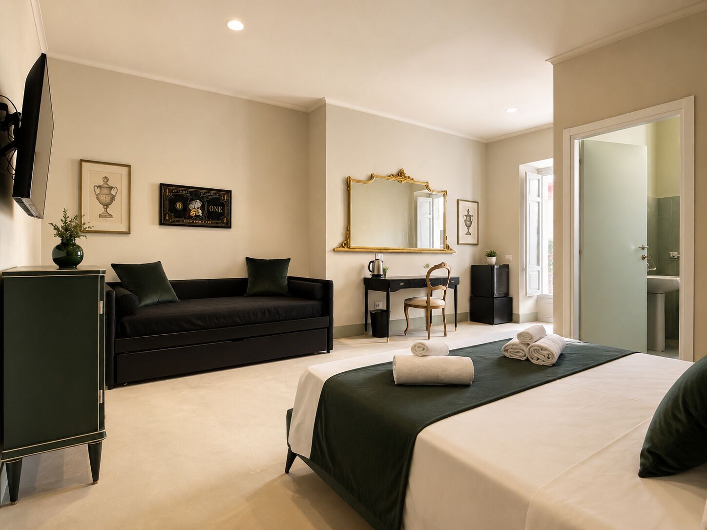A hotel room with a bed, a desk, a chair, a television, and artwork on the walls.