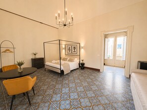 A bedroom with a four-poster bed, a chandelier, a dining table with chairs, and patterned floor tiles. - 4 Canti Rooms (Avola)