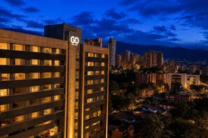 A high-rise building with a prominent 'GO' sign, surrounded by a cityscape at dusk. - New Loft near Milla de Oro with AC and coworking (Medellín)