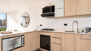 Una cucina moderna con forno integrato, microonde e lavastoviglie, un'ampia finestra e vista sulla città.