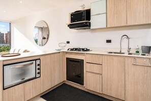 Eine moderne Küche mit Einbauofen, Mikrowelle und Geschirrspüler, einem großen Fenster und Blick auf die Stadt.
