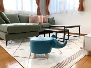 A modern living room with a green sofa, a blue ottoman, and a coffee table. - Neo Universal 05 (Osaka, Konohana, Nishikujo)