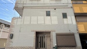A two-story building with a flat roof, a central entrance with a door, and two windows on the upper floor. - Neo Universal 05 (Osaka, Konohana, Nishikujo)
