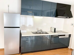 Eine moderne Küche mit Kühlschrank, Spüle, Geschirrspüler und Schränken.