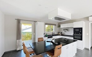 A modern kitchen with a central island, white cabinetry, and a black countertop. - Villa nestled between the mountains and the Basque Country (Sauvagnon)