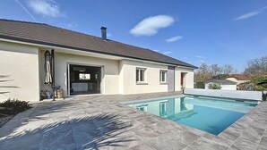 Ein Haus mit Swimmingpool, Garage und einer Terrassenfläche.