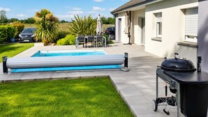 Ein Wohnhaus mit Swimmingpool, Sitzgelegenheiten im Freien und Grill.