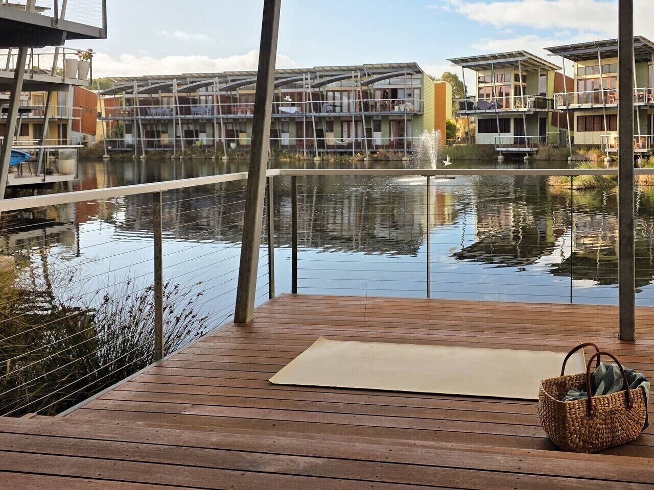 A wooden deck with a view of a water body and buildings in the background.