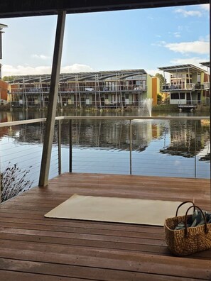 A wooden deck with a view of a water body and buildings in the background.