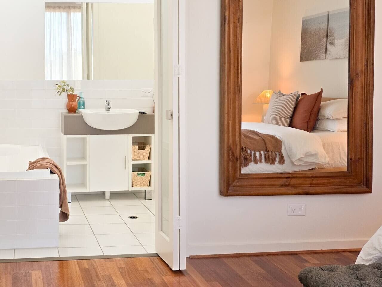 A modern bathroom with a white sink, mirror, and white cabinets.