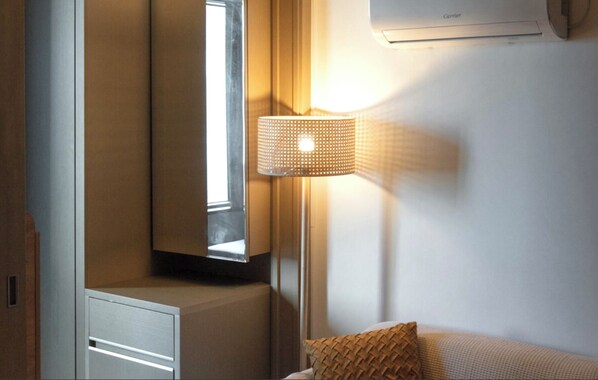 Une pièce avec un lit, une lampe, une fenêtre et un climatiseur.
