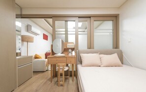 Un dormitorio con cama, escritorio, silla, espejo, mesita de noche y armario.