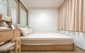 Une chambre à coucher avec un lit, un bureau avec une chaise, une lampe et une fenêtre avec des rideaux.