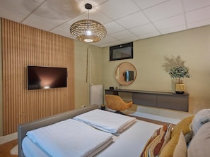 Een hotelkamer met een bed, een televisie, een spiegel, een bureau en een plant.