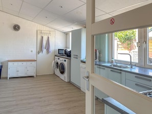 Een kleine keuken met een wasmachine, een magnetron en een spoelbak.