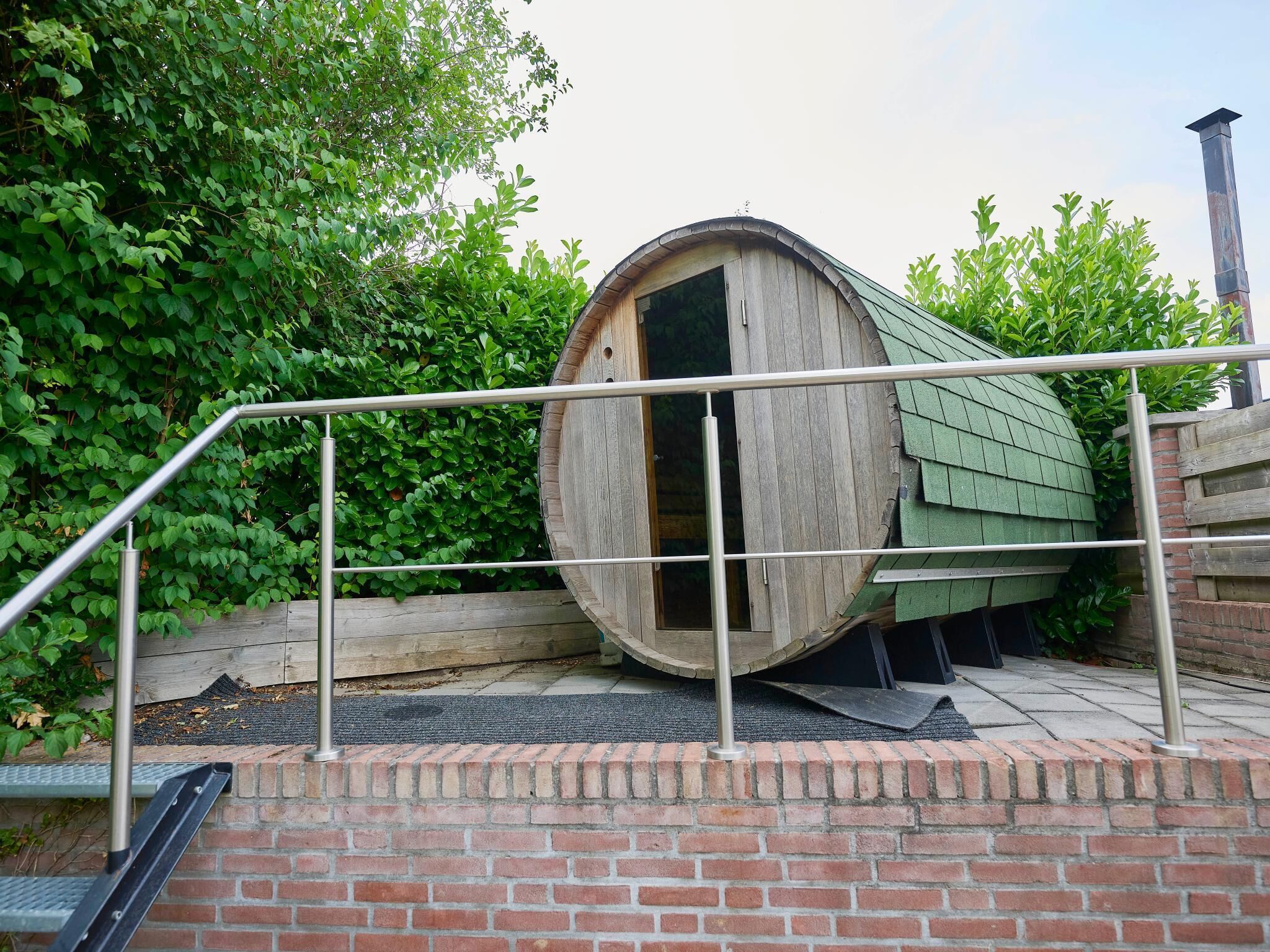 A barrel-shaped structure with a door, surrounded by a metal railing and brick steps.