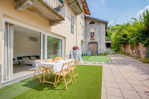 Eine Terrasse mit Frühstückstisch, ein überdachter Außenbereich zum Sitzen und ein Gebäude mit einer Stein-Fassade.