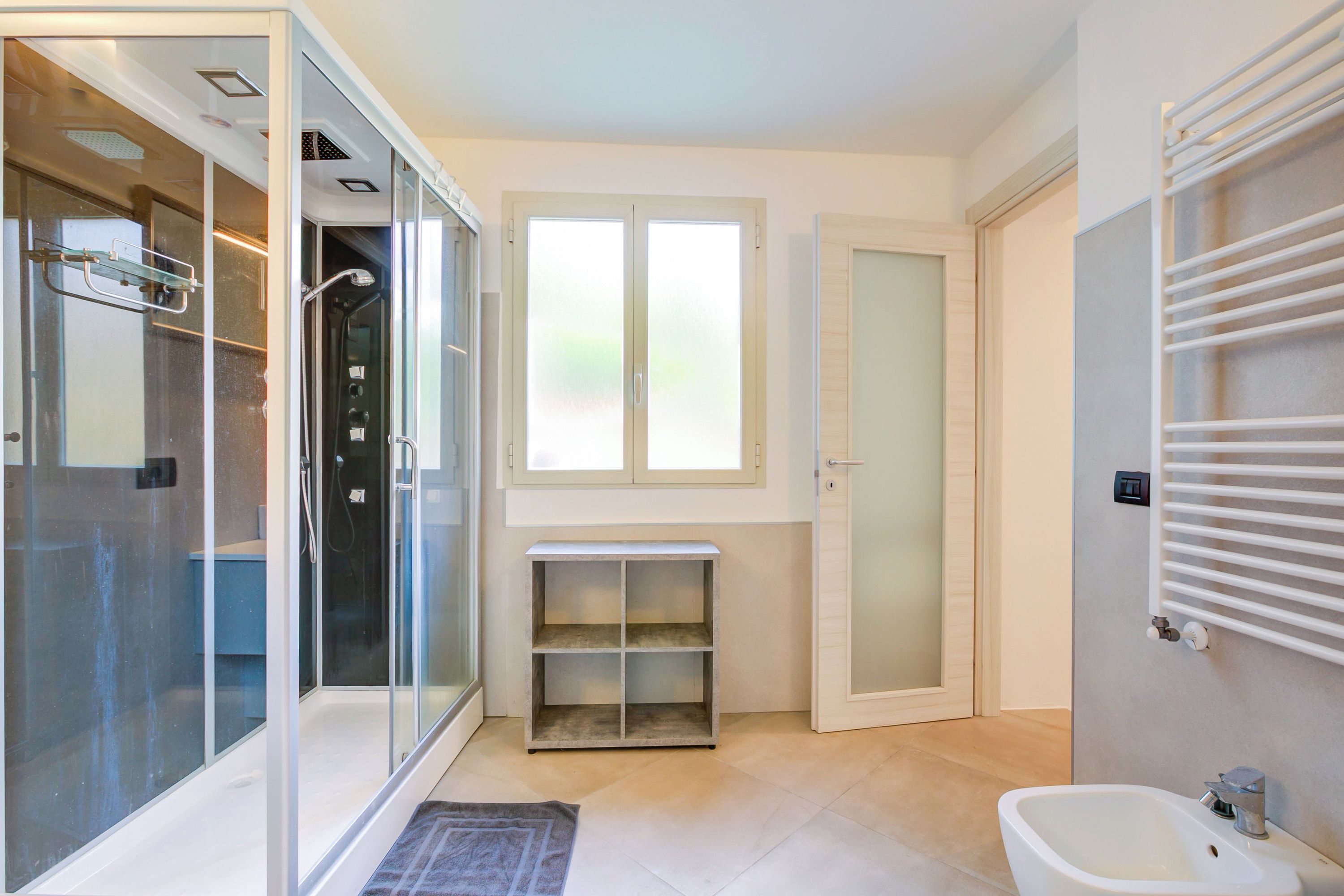 Een moderne badkamer met een douchecabine van glas, een ingebouwd wastafelmeubel en een handdoekrek.