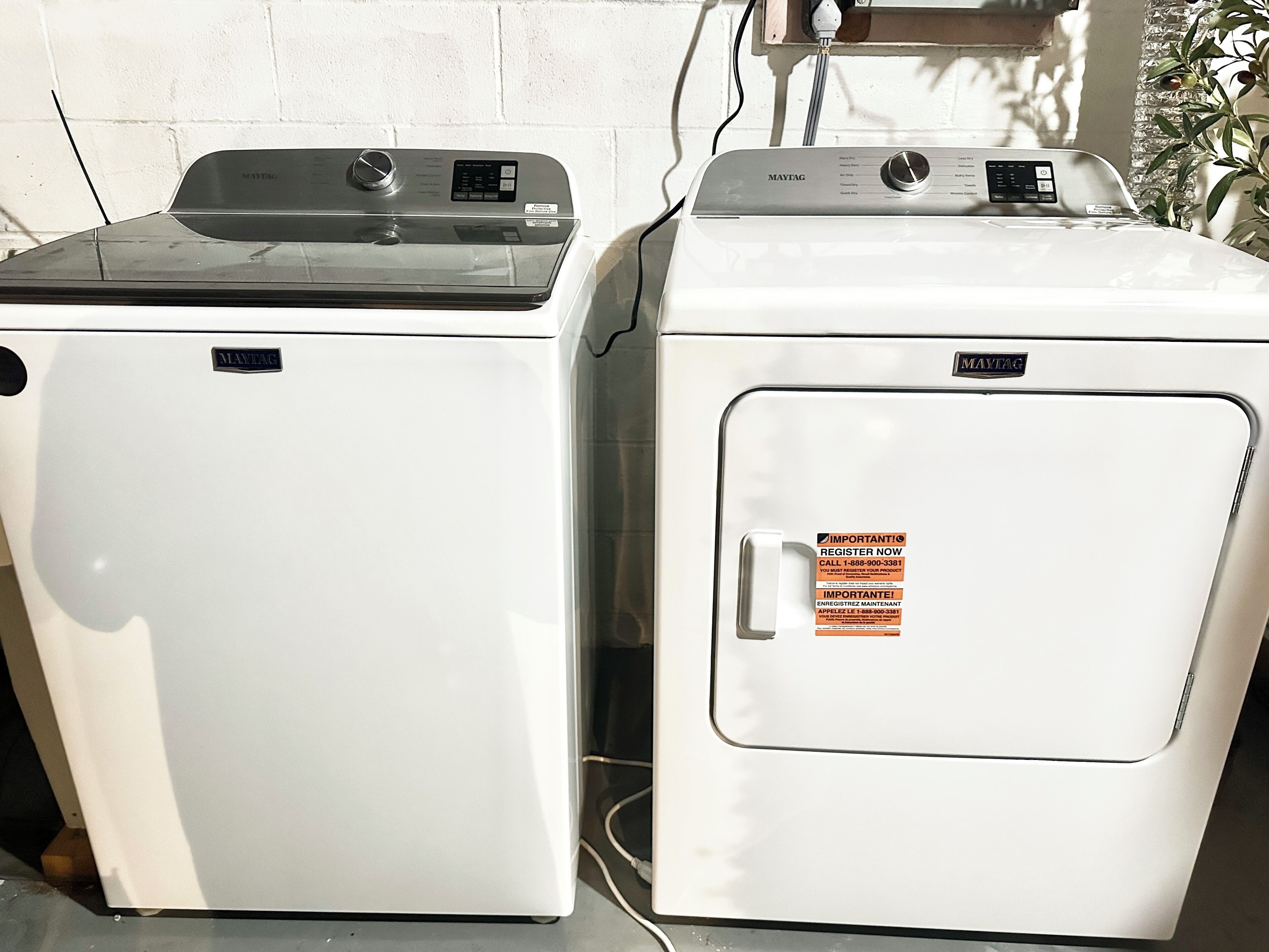 Two white washing machines side by side, one with a black top and the other with a silver top, both with control panels and brand labels.