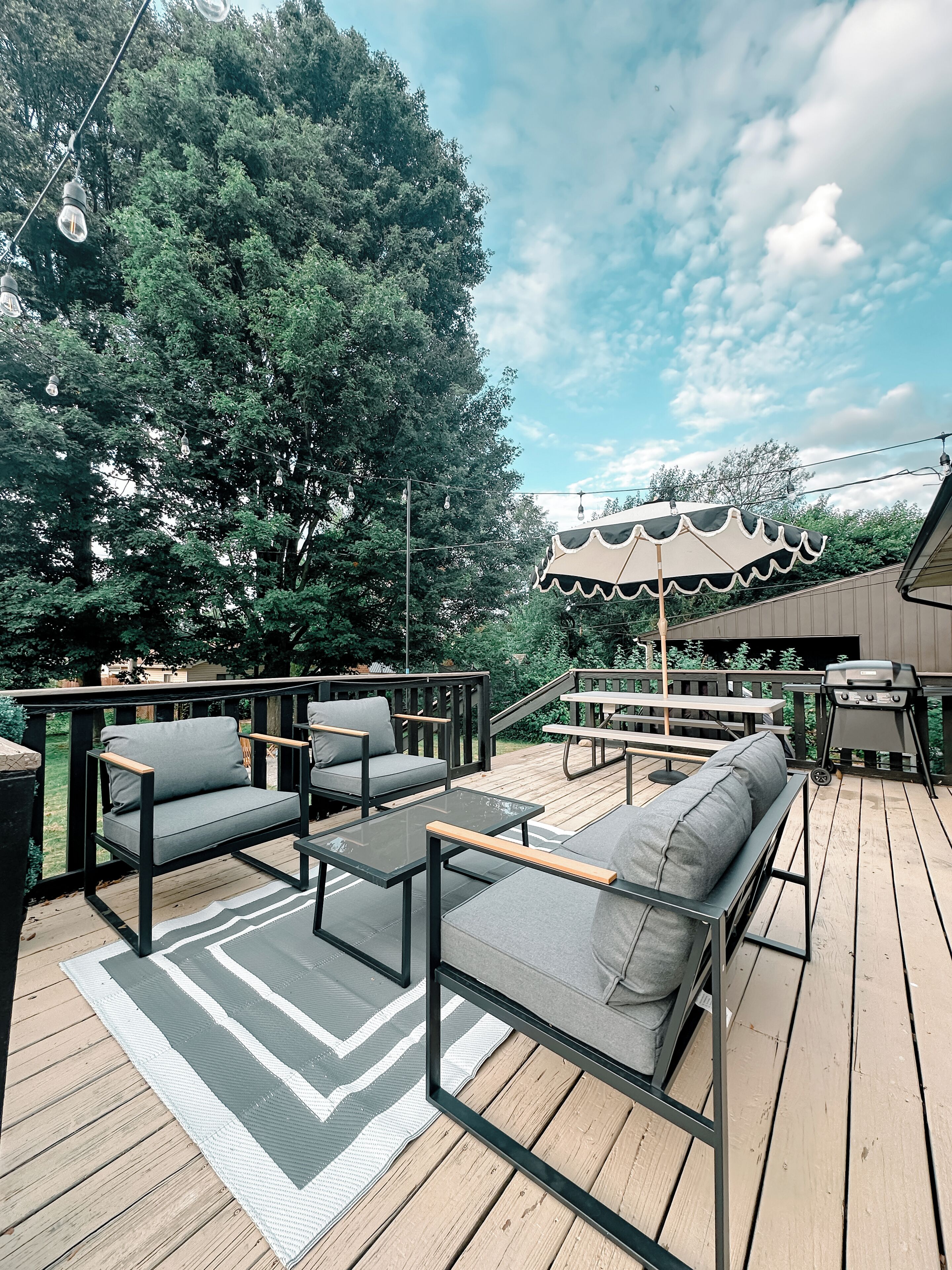 An outdoor deck with seating, a grill, and a picnic table.