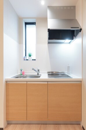 A modern kitchen with a window, stainless steel sink, and wooden cabinets. - SERENE│Kuromon ・ Entire Japanese private home│ 4 bedrooms ・ 3 bathrooms│ 30 seconds to Kuromon (Osaka)