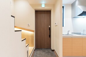 A narrow hallway with a wooden door, a light switch, and a small window. - SERENE│Kuromon ・ Entire Japanese private home│ 4 bedrooms ・ 3 bathrooms│ 30 seconds to Kuromon (Osaka)