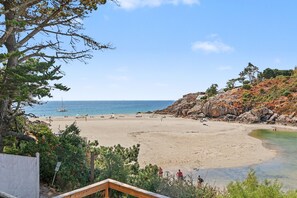 Ein Strand mit blauem Himmel, felsigem Gelände und ruhiger See.