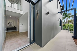 A modern house with a glass door entrance, a visible kitchen area, and a balcony with potted plants. - Burleigh Vista, Burleigh Heads (Burleigh Heads)
