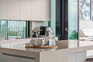A modern kitchen with a central island, a coffee machine, and a view of the outdoors. - Burleigh Vista, Burleigh Heads (Burleigh Heads)