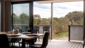 A dining area with a table set for four, chairs, and a view through a glass door to the outdoors.