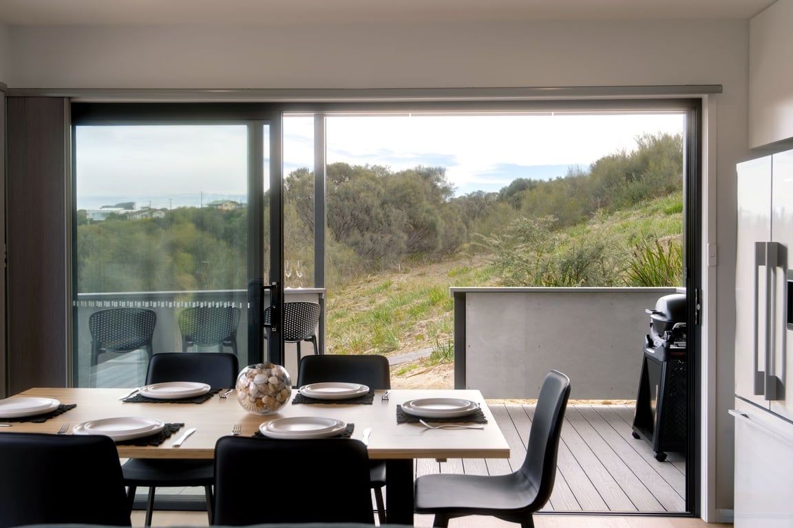 A dining area with a table set for four, overlooking a natural landscape.